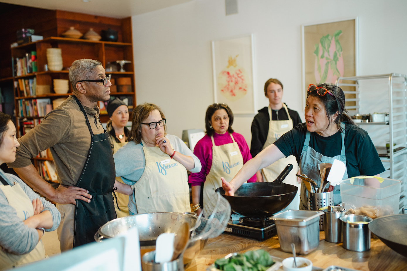 A class gathers around the instructor at the 18th Street Kitchen