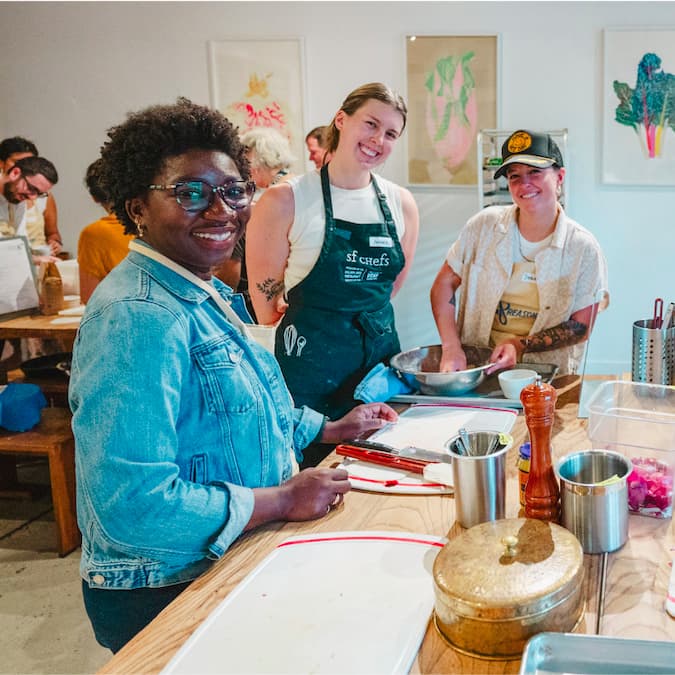 People smiling around a table that has baking supplies on it